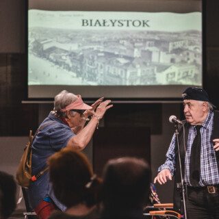 kabaret lumbago podczas występu z fotografią w tle przedctawiającą miasto białystok oraz z udziałem publiczności w domu kultury śródmieście w białymstoku