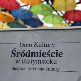 tablica domu kultury śródmieście w białysmtoku na tle kolorowych parasolek