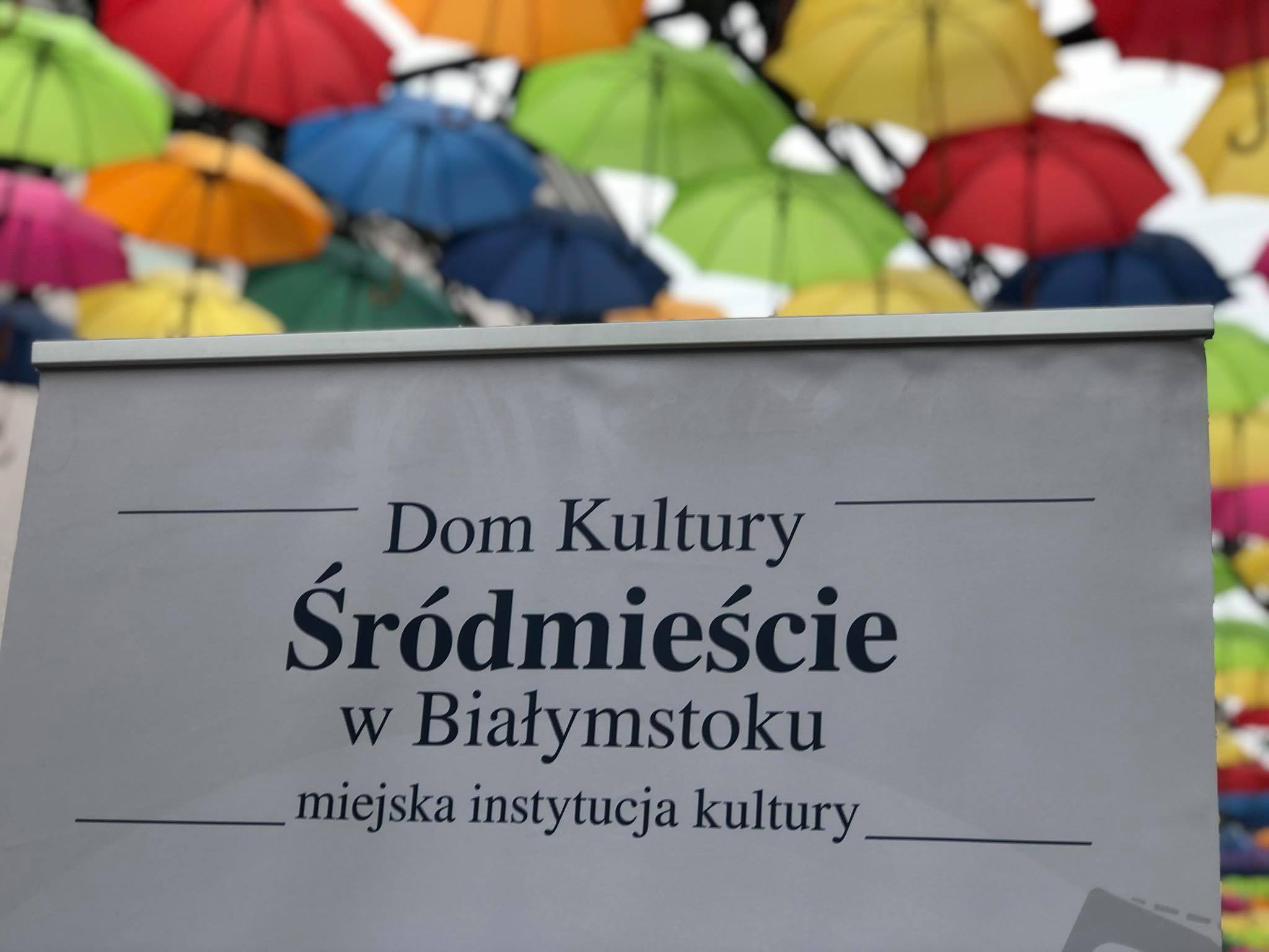 tablica domu kultury śródmieście w białysmtoku na tle kolorowych parasolek