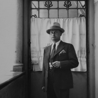 czarno-biała fotografia mężczyzny w kapeluszu i garniturze stojącego przed drzwiami w domu kultury śródmieście w białymstoku Wernisaż wystawy "Latency" Jozefa Sedláka INTERPHOTO