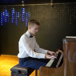 uczestnik zajęć artystycznych grający na pianinie podczas koncertu bożonarodzeniowego w domu kultury śródmieście w białymstoku