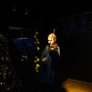 uczestniczka zajęć artystycznych grająca na skrzypcach podczas koncertu bożonarodzeniowego w domu kultury śródmieście w białymstoku