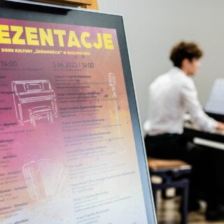 plakat prezentacje w domu kultury śródmieście w białymstoku zawierający harmonogram w tle gra członek ogniska muzycznego na pianinie