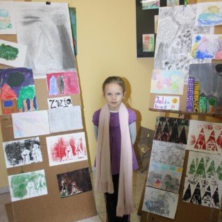 dziewczynka stojąca obok kolażu z prac dzieci z artystycznych ferii zimowych w dkś