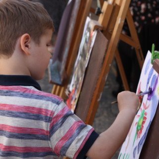 człopiec malujący pędzlem z farbami po kartce na sztaludze dkś